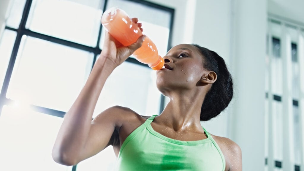 african american woman drinking an energy drink at the gym